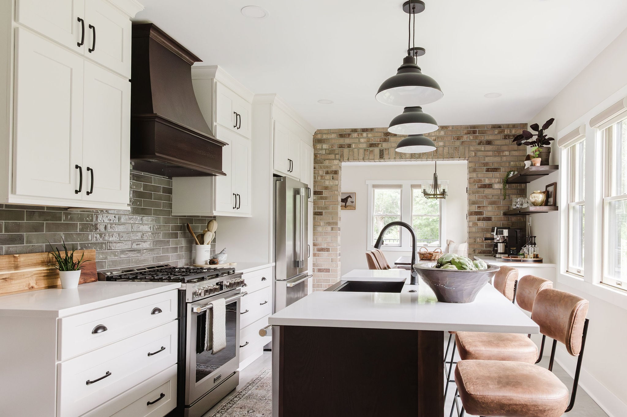 Farmhouse kitchen with creamy white cabinets, dark hickory hood and island, and brick archway